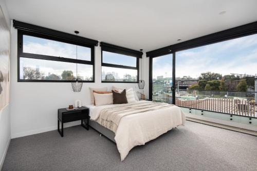 - une chambre avec un lit et de grandes fenêtres dans l'établissement Sport Precinct Luxury Style over four levels, à Melbourne