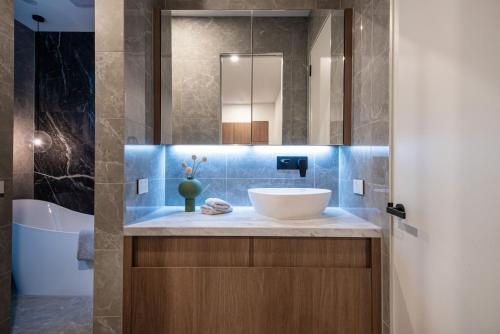 La salle de bains est pourvue d'un lavabo et d'une baignoire. dans l'établissement Sport Precinct Luxury Style over four levels, à Melbourne