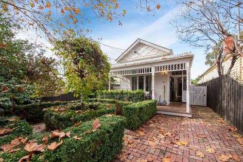 una casa blanca con una pasarela de ladrillos frente a un patio en Timeless Gem in Malvern East, en Carnegie