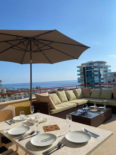 una mesa con platos y una sombrilla en el balcón en Penthouse Paradise in Mahmutlar, en Alanya