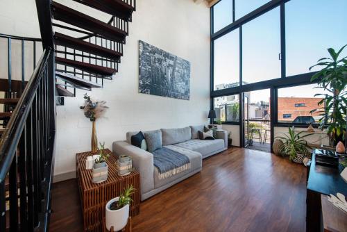a living room with a couch and some plants at Loft Living Close to the MCG in Melbourne