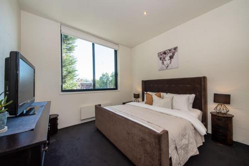 a bedroom with a large bed and a window at Loft Living Close to the MCG in Melbourne