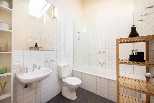 a bathroom with a toilet and a sink and a tub at Loft Living Close to the MCG in Melbourne