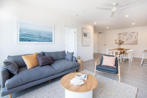 ein Wohnzimmer mit einer blauen Couch und einem Tisch in der Unterkunft Beachfront Apartment with lots of Wow in Rosebud