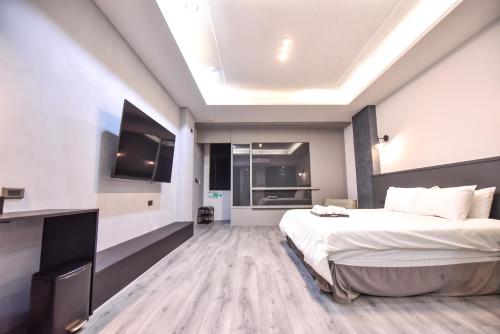 a bedroom with a large bed and a television at Two Couples Leisure Art Motel in Tainan