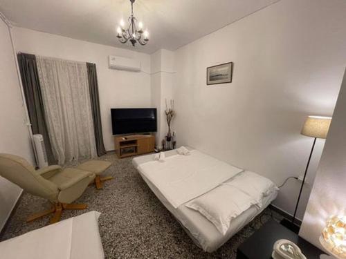 a bedroom with a bed and a chair and a television at Casa Palmera Beach Apartment in Áyios Andónios