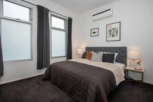 a bedroom with a large bed and two windows at Elwood Village Entertainer in Melbourne