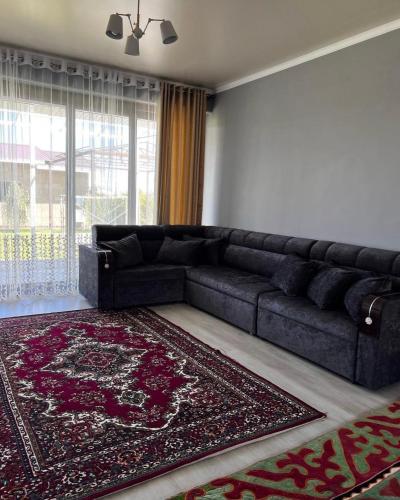 eine schwarze Couch in einem Wohnzimmer mit einem Teppich in der Unterkunft Коттедж в отеле Палм Бич Иссык Куль in Chok-Tal