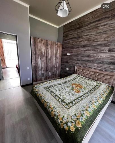 ein großes Bett in einem Zimmer mit einer Holzwand in der Unterkunft Коттедж в отеле Палм Бич Иссык Куль in Chok-Tal