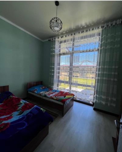 1 Schlafzimmer mit 2 Betten und einem großen Fenster in der Unterkunft Коттедж в отеле Палм Бич Иссык Куль in Chok-Tal