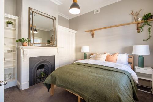a bedroom with a bed with a fireplace and a mirror at Sandy Village Retreat Heated Pool Bay Views in Sandringham