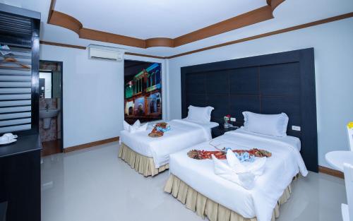 a bedroom with two beds with white sheets at Blue Carina Hotel Phuket in Phuket Town