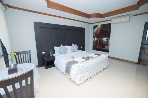 a bedroom with a large white bed and a table at Blue Carina Hotel Phuket in Phuket Town