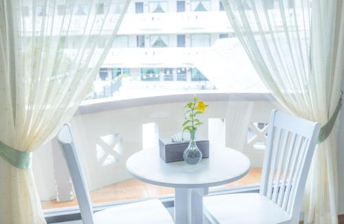 a table and two chairs in a room with a window at Blue Carina Hotel Phuket in Phuket Town