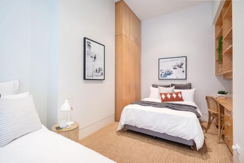 a bedroom with two beds and a desk at Grand Victoria Beach House in Melbourne