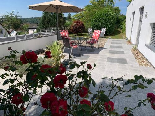 un patio con 2 sillas, una sombrilla y rosas en Panorama Apartment, en Kandern