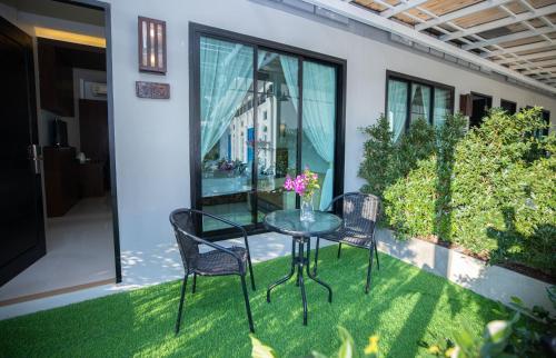 a glass table and two chairs on a patio at Blue Carina Hotel Phuket in Phuket Town
