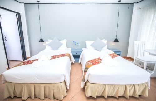 a bedroom with two beds with white sheets at Blue Carina Hotel Phuket in Phuket Town