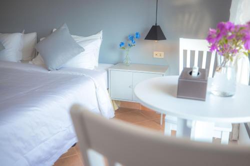 a bedroom with a white bed and a table with flowers at Blue Carina Hotel Phuket in Phuket Town