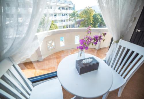 a white table with a vase of flowers on a balcony at Blue Carina Hotel Phuket in Phuket Town