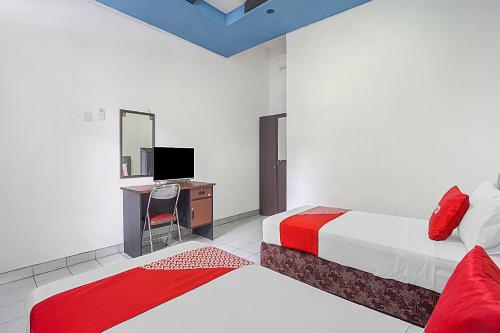 een slaapkamer met 2 bedden, een bureau en een televisie bij Collection O 90589 Palem Garden Hotel in Tulungagung
