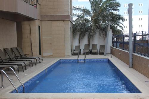 a swimming pool in a building with chairs and palm trees at Times Square Suite Hotel in Kuwait