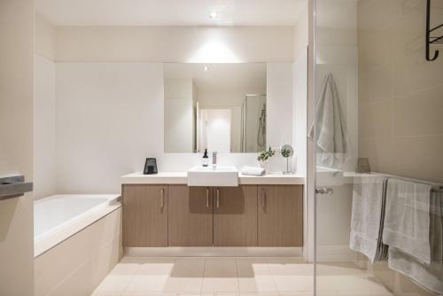 uma casa de banho com um lavatório, uma banheira e um espelho. em Luxe on Main in Mornington Views of the Bay em Mornington