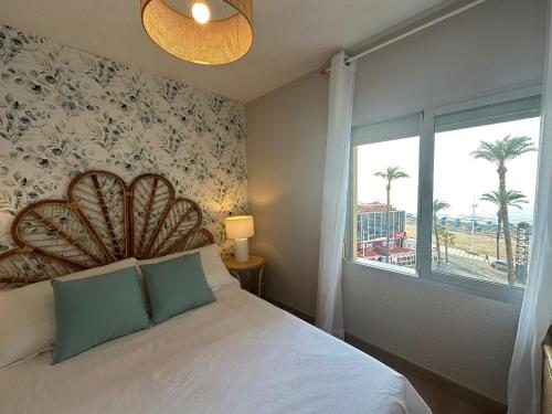 a bedroom with a bed and a window with palm trees at Apartamento La Concha PLAYA DE LEVANTE in Benidorm