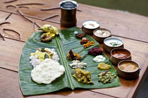 a green plate of food on a wooden table at Niraamaya Wellness Retreats, Surya Samudra, Kovalam in Kovalam