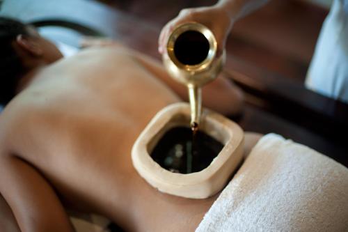 a man with no shirt on is getting his hair brushed at Niraamaya Wellness Retreats, Surya Samudra, Kovalam in Kovalam