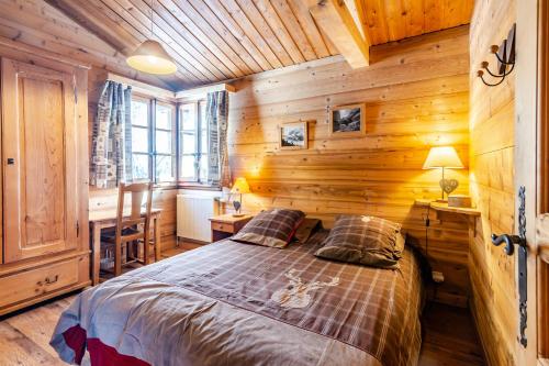 ein Schlafzimmer mit einem Bett in einer Holzhütte in der Unterkunft chalet les ecureuils in Saint-Jean-de-Sixt