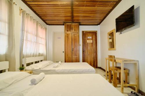 a room with three beds and a television in it at Pallet Homes - Ledesco in Iloilo City
