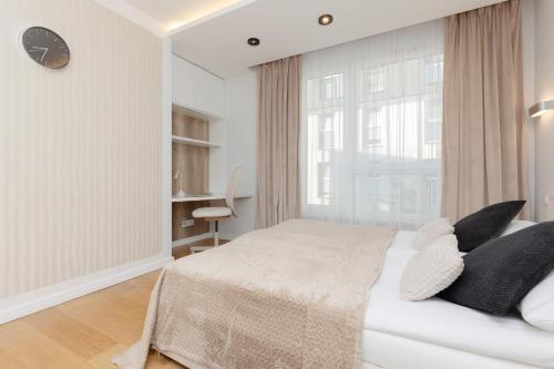 a white bedroom with a bed and a window at Spacious Lodygowa Apartment Ideal for Families by Renters in Warsaw