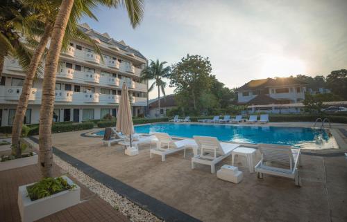 a resort with a pool and chairs and a hotel at Blue Carina Hotel Phuket in Phuket Town