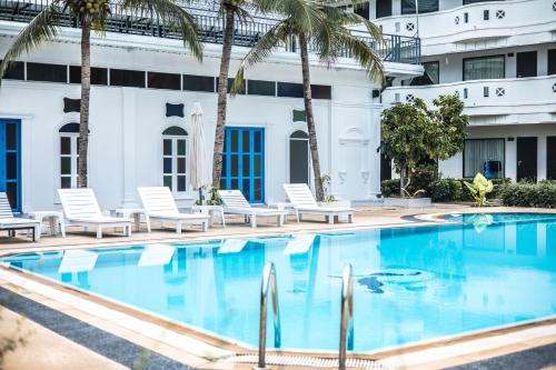 a pool in front of a hotel with chairs and palm trees at Blue Carina Hotel Phuket in Phuket Town