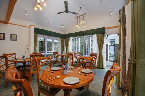 een eetkamer met een houten tafel en stoelen bij Summit Bougainvillea Tea Resort in Kurseong