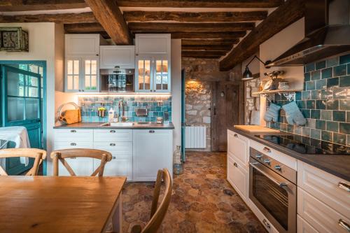 une cuisine avec des armoires blanches et une table et des chaises dans l'établissement Maison du Chapelain, à Duclair