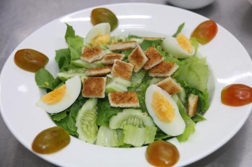 a white plate with a salad with eggs and tomatoes at White Corner Hotel in Phnom Penh