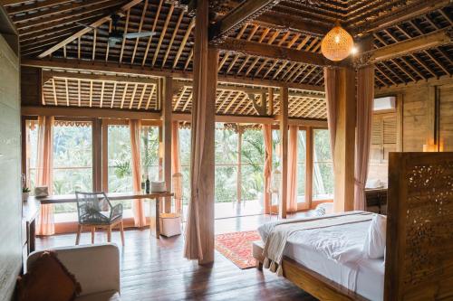 1 dormitorio con 1 cama en una habitación con ventanas en Ubud Riverside Villa, en Ubud