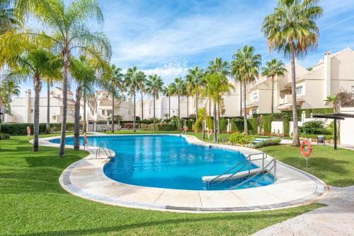 ein Swimmingpool in einem Resort mit Palmen in der Unterkunft El Arenal Townhouse By The Beach With Swimming Pool - EaW Homes in Marbella