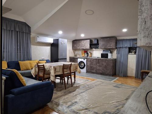 a living room with a table and a kitchen at GUEST HOUSE 15A in Kutaisi