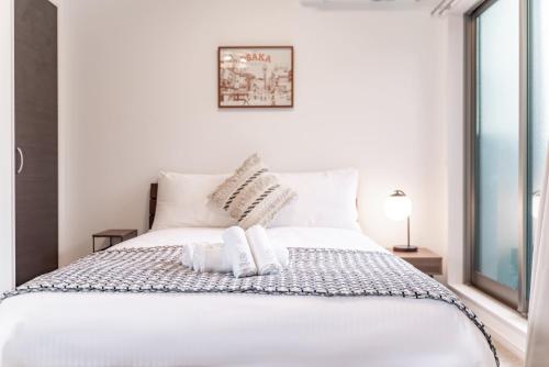 a white bed with two pillows on top of it at 川HOUSE旭 in Osaka