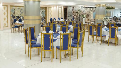 a dining room with blue and gold chairs and tables at Faletti's Express- Shimla Hill in Lahore