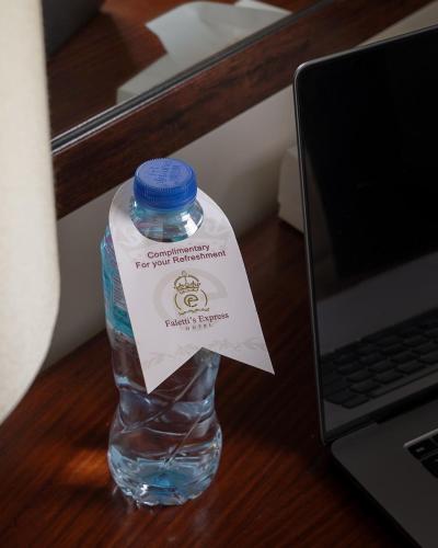 a bottle of water sitting on a desk next to a laptop at Faletti's Express- Shimla Hill in Lahore