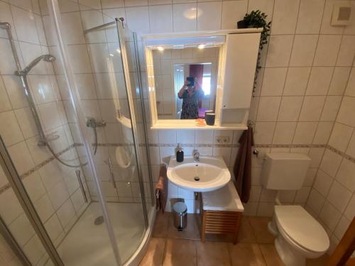 une personne prenant une photo d'une salle de bains avec lavabo et douche dans l'établissement Gemütliches Ferienapartement, à Cassel