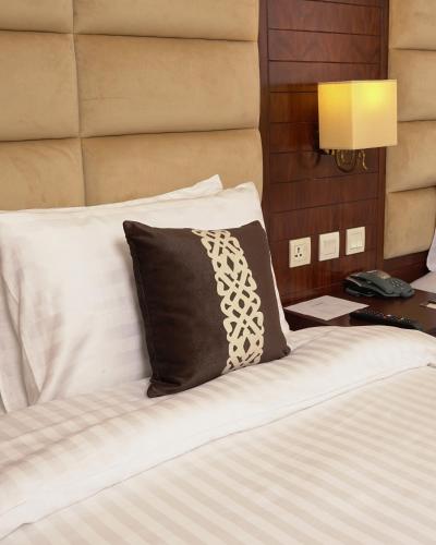 a bed with a black and white pillow on it at Faletti's Express- Shimla Hill in Lahore