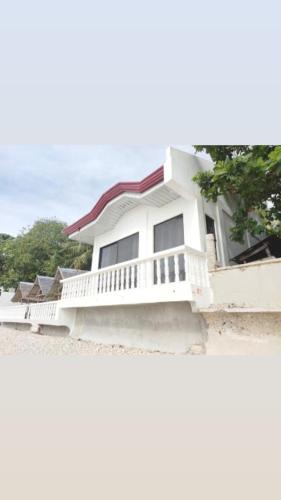 a white house with a balcony and the ocean at LUNA OSLOB TRAVELLERS INN - Beach Front in Oslob