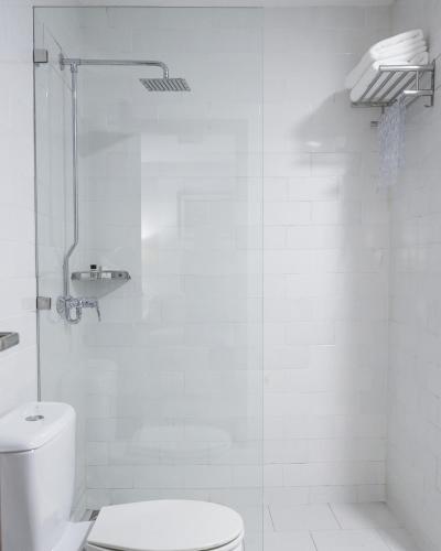 a white bathroom with a toilet and a shower at Faletti's Express- Shimla Hill in Lahore