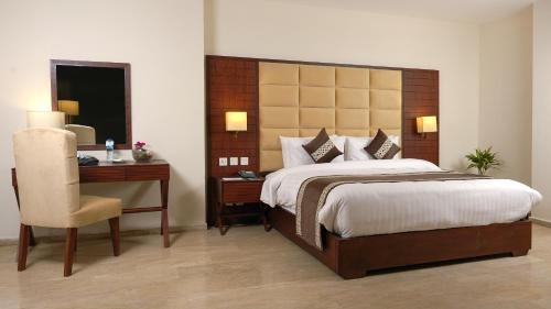 a bedroom with a bed and a desk and a chair at Faletti's Express- Shimla Hill in Lahore