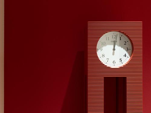 a clock on a wall with a red wall at Hotel Il Palazzo in Fukuoka